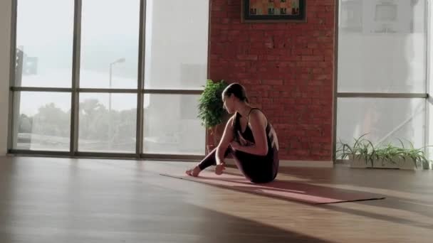 Mujer joven en uniforme deportivo rojo tratando de hacer Astavakrasana asana en estudio de yoga. Ejercicio de equilibrio — Vídeo de stock