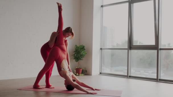 Vrouw yoga leraar helpt student om de Eka Pada Adho Mukha Svanasana correct te doen. Fouten in yoga — Stockvideo