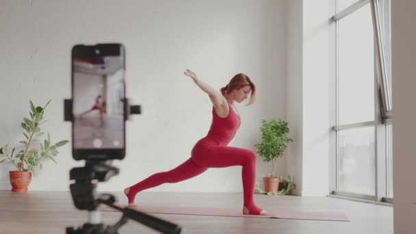 Yoga hocası cep telefonuyla spor yapıyor. Ev ödevi yoga kavramı — Stok video