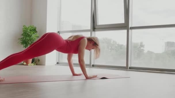 Schöner Yoga. Junge Frau in roter Sportuniform macht glatte Körperwindungen. Gesunder Lebensstil — Stockvideo