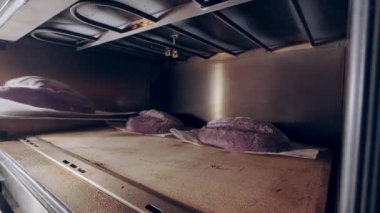 Baker pişirmek için fırına çiğ ekmek koyar. Pişirme üretimi. Çevrim içi tarifler 