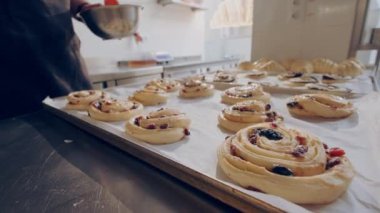 Baker pişirmeden önce çiğ böğürtlenli salyangoz çöreğine yumurta sarısı sürer. Pişirme süreci.