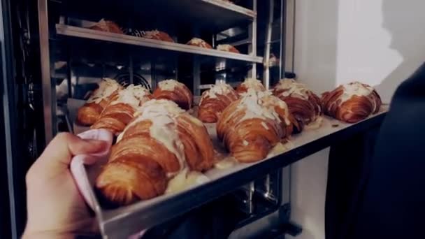 Baker legt bakplaat van Franse croissants met amandelpasta in de oven om te bakken. Sluiten. — Stockvideo