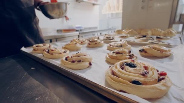 Il panettiere spalma focacce crude di escargot di bacche con tuorlo d'uovo prima della cottura. Processo di cottura. — Video Stock