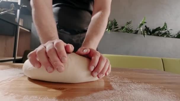 Man boulanger pétrit la pâte pour la cuisson et le pain sur une table en bois. Au ralenti. Procédé de cuisson fait maison — Video