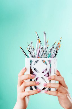 Manikürlü kadın elleri bir sürü manikür fırçası tutar. Katalog fotoğrafı