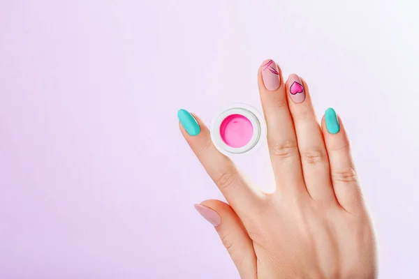Foto de catálogo de manicure. Bela mão feminina segura gel de unhas para manicure no fundo rosa — Fotografia de Stock