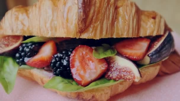 Superbe croissant de baies dorées croustillantes aux fraises, mûres et basilic sur assiette rose. — Video