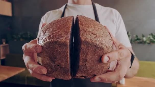 Pane fresco bello rotondo. Il fornaio mostra il pane scuro rotondo appena sfornato in taglio. Primo piano. — Video Stock