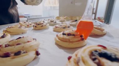 Baker pişirmeden önce çiğ böğürtlenli salyangoz çöreğine yumurta sarısı sürer. Pişirme süreci.
