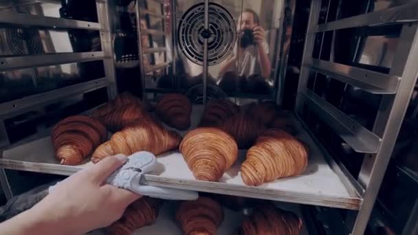 Baker mengambil almond baru dipanggang diisi croissant keluar dari oven. Proses pemanggang — Stok Video