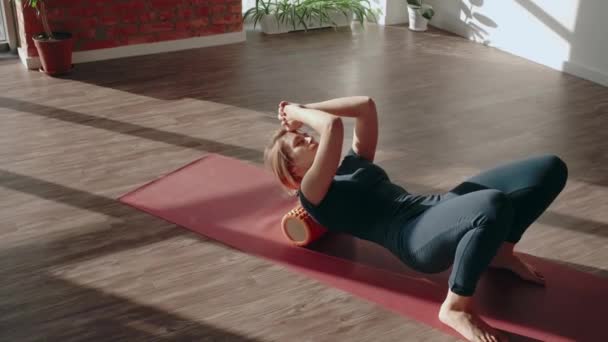 Rollertraining van achteren. Vrouw doet stretching en spiermassage met schuimroller na de training — Stockvideo