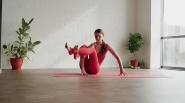 Kırmızı spor üniformalı genç kadın yoga stüdyosunda Astavakrasana Asana 'yı sahneliyor. Denge egzersizi