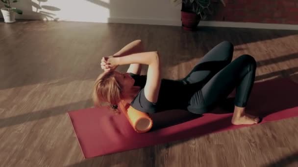 Entrenamiento de rodillo de espalda. Mujer haciendo estiramiento y masaje muscular con rodillo de espuma después del entrenamiento — Vídeos de Stock