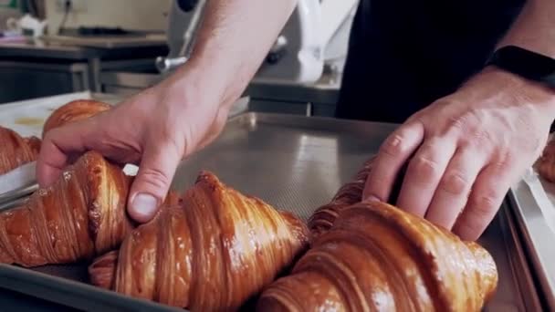 Piekarz umieszcza świeżo upieczone francuskie rogaliki na blasze. Zamknij drzwi. Produkcja pieczenia — Wideo stockowe