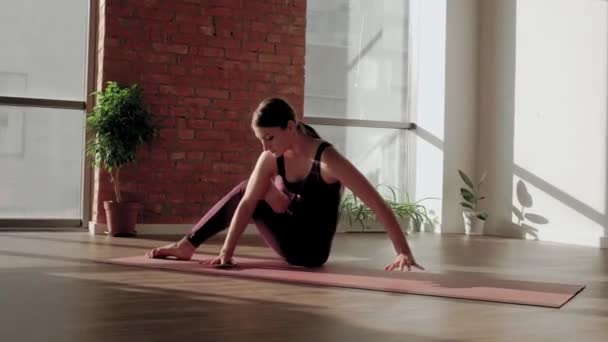 Junge Frau in roter Sportuniform führt Astavakrasana Asana im Yoga-Studio vor. Gleichgewichtsübung — Stockvideo