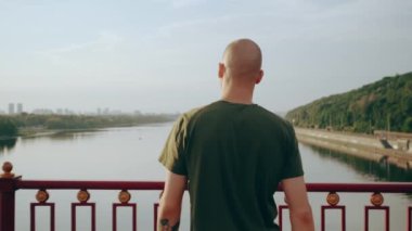 Genç adam nehre bakan yaya köprüsünde dururken esniyor. Sabahın tadını çıkarıyorum.