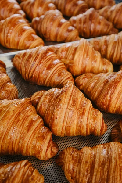 Hand takes fresh golden French croissant from the baking sheet. Fresh classic pastries