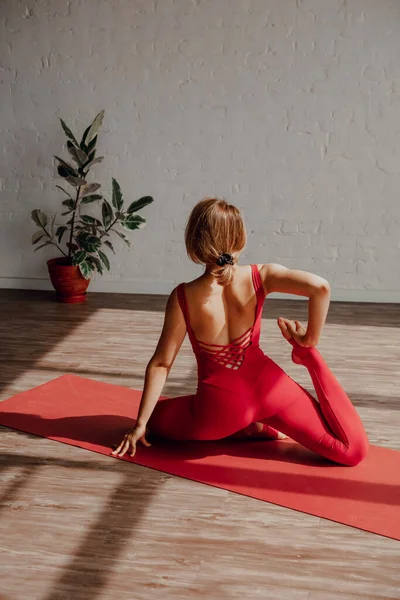 健康的生活方式 身穿红色运动服的年轻女子在轻便瑜伽演播室里伸展腿 拖延时间 高质量的照片 免版税图库图片