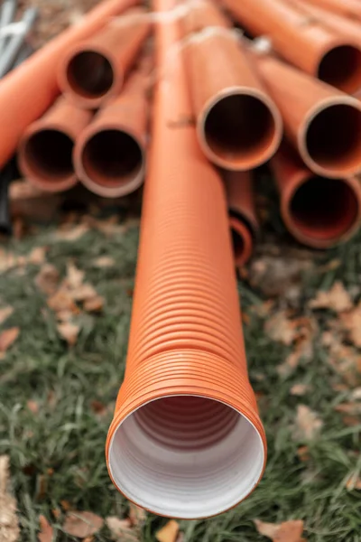 新しいオレンジプラスチック下水道管は屋外に位置しています 異なる直径のパイプを持つ建設現場 高品質の写真 ストック写真