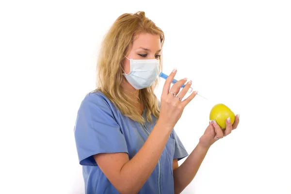 Young woman doctor injecting green apple with syringe — Stock Photo, Image