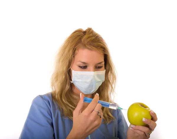 Young woman doctor injecting green apple with syringe — Stock Photo, Image