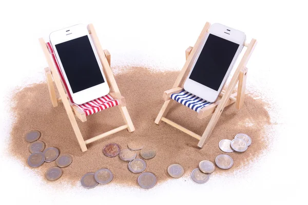 Twee mobiele telefoons in speelgoed strand stoelen — Stockfoto