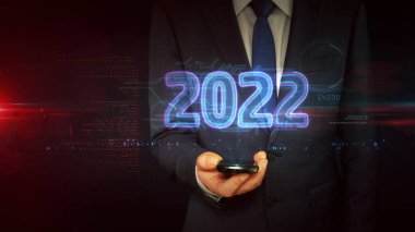 2022 yılı, yeni siber tasarım konsepti. İş adamı elindeki holograma dokunuyor. Fütürist ışık sembolü soyut.