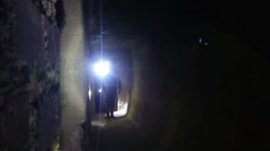 Yeraltı tünelleri. Mağara ve mağara keşfi. Beton sığınakların harabelerinde yürüyorlar. Fenerli bir adam eski Alman askeri güçlerinden geçiyor..