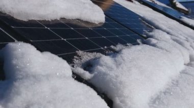 Güneş paneli kış mevsiminde çatıda. Karla kaplı fotovoltaik enerji santrali. Özel ev elektrik tesisatı. Yenilenebilir yeşil güneş enerjisi. Kamera paneller üzerinde hareket ediyor.