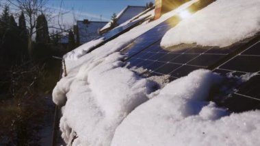 Güneş paneli kış mevsiminde çatıda. Karla kaplı fotovoltaik enerji santrali. Özel ev elektrik tesisatı. Yenilenebilir yeşil güneş enerjisi. Kamera paneller üzerinde hareket ediyor.