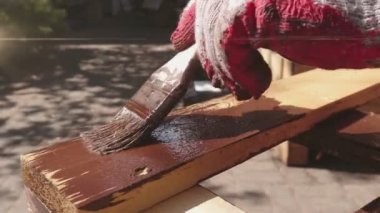 Ev bahçesinde ahşap boyama. Boya fırçasıyla ahşap element koruması.