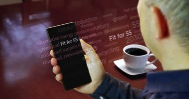 The man is reading the articles on smartphone. Headline news across media about the Fit for 55 green deal reduce the greenhouse gas emissions. Abstract concept of news titles on phone in hand.