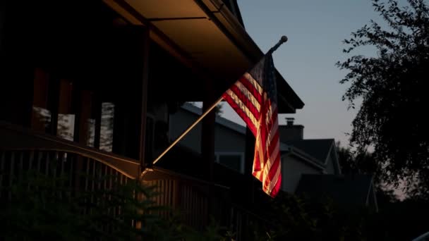 De Amerikaanse vlag is bevestigd aan een prive-huis en verlicht door verlichting 's nachts. Close-up zicht — Stockvideo