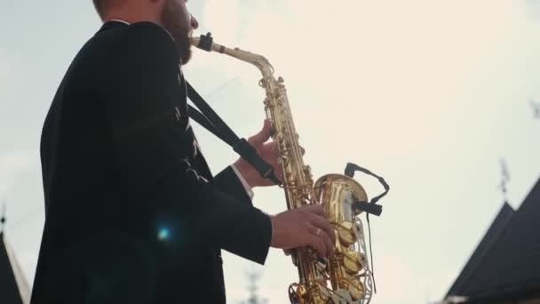 Muzikant saxofonist speelt muziek op zijn instrument in een zonnige zomerdag. Close-up fusie — Stockvideo