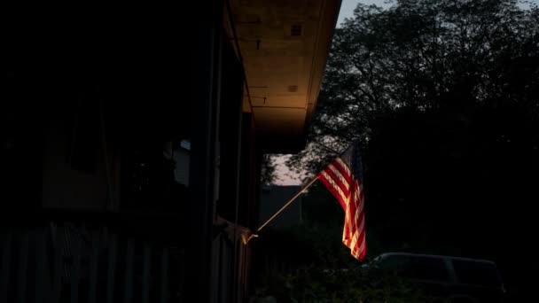 De Amerikaanse vlag is bevestigd aan een prive-huis en verlicht door verlichting 's nachts. Close-up fusie — Stockvideo