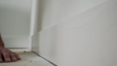 Duvarı silindirle boyayan bir ressam. Kalıpların üstünde kullanışlı boya, süpürgelik. Yavaş çekim. Yakın çekim.