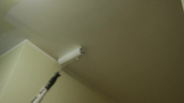 Duvarı silindirle boyayan bir ressam. Duvarın üstünde kullanışlı bir tablo. Çekim tarihini kapat