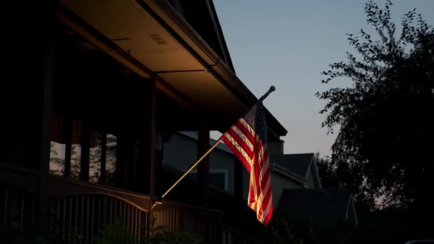 La bandera americana está unida a una casa privada e iluminada por la iluminación nocturna. De cerca. — Vídeos de Stock