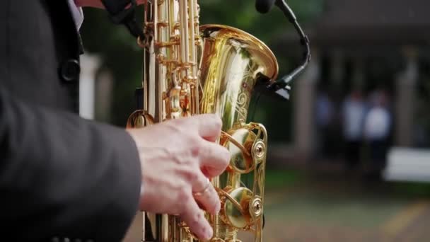 Primer plano futage de músico saxofonista toca música en su instrumento en un soleado día de verano. Movimiento lento — Vídeo de stock