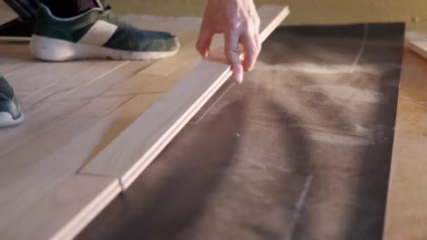 View of Man installing parquet floor tiles over white foam base layer, hammering nails in with a special hammer — Stock Video