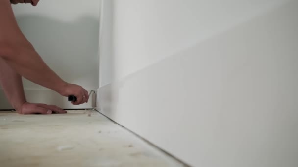 Vista de cerca del pintor pintando el borde de la pared con rodillo. Práctico cuadro sobre molduras, zócalo. Movimiento lento — Vídeo de stock