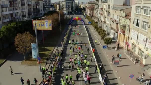 Vista aérea del dron de Runners, comenzando su marca desde la línea de salida del maratón en las tranquilas calles de la ciudad 9.10.2021 Ivano Ukraina — Vídeos de Stock