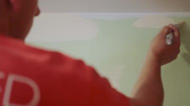 Ressam, duvarı fırçayla boyuyor. Duvarın üstünde kullanışlı bir tablo. Kapat...