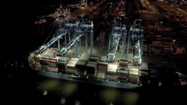 Воздушный обзор грузового судна с грузовыми контейнерами стоит на причале в порту при погрузке и выгрузке контейнеров в ночное время. — стоковое видео