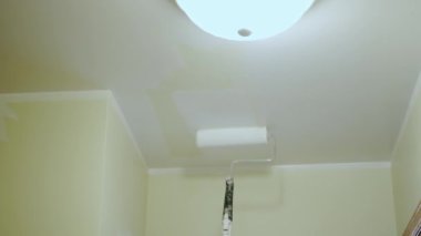 Duvarı silindirle boyayan bir ressam. Duvarın üstünde kullanışlı bir tablo. Geleceği kapat..