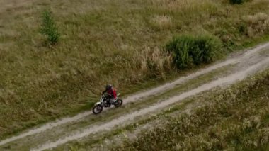 Taşra yolunda giden motosikletli sürücülerin hava aracı görüntüsü.