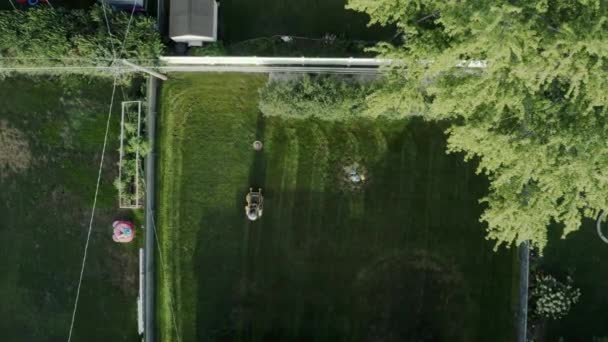 Bovenaanzicht vanuit de lucht van een grasmaaimachine van bovenaf op de achtertuin — Stockvideo