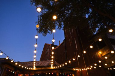 Açık terasta asılı ampullerin geniş açılı görüntüsü, sıcak ışık kaynağı. 