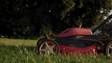 Man 'in oyun parkındaki salıncağın yanında çim biçme makinesiyle çimleri biçtiği görüntüleri kapatın. Yavaş çekim görüntüleri